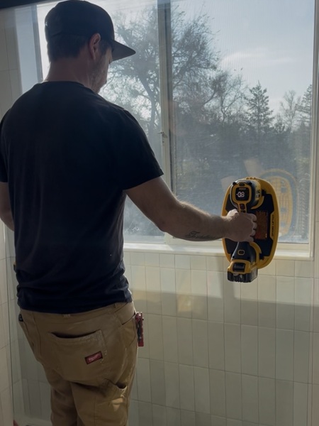 Professional contractor using the Dewalt 20V Max Grabo Lifter to install shower glass panel