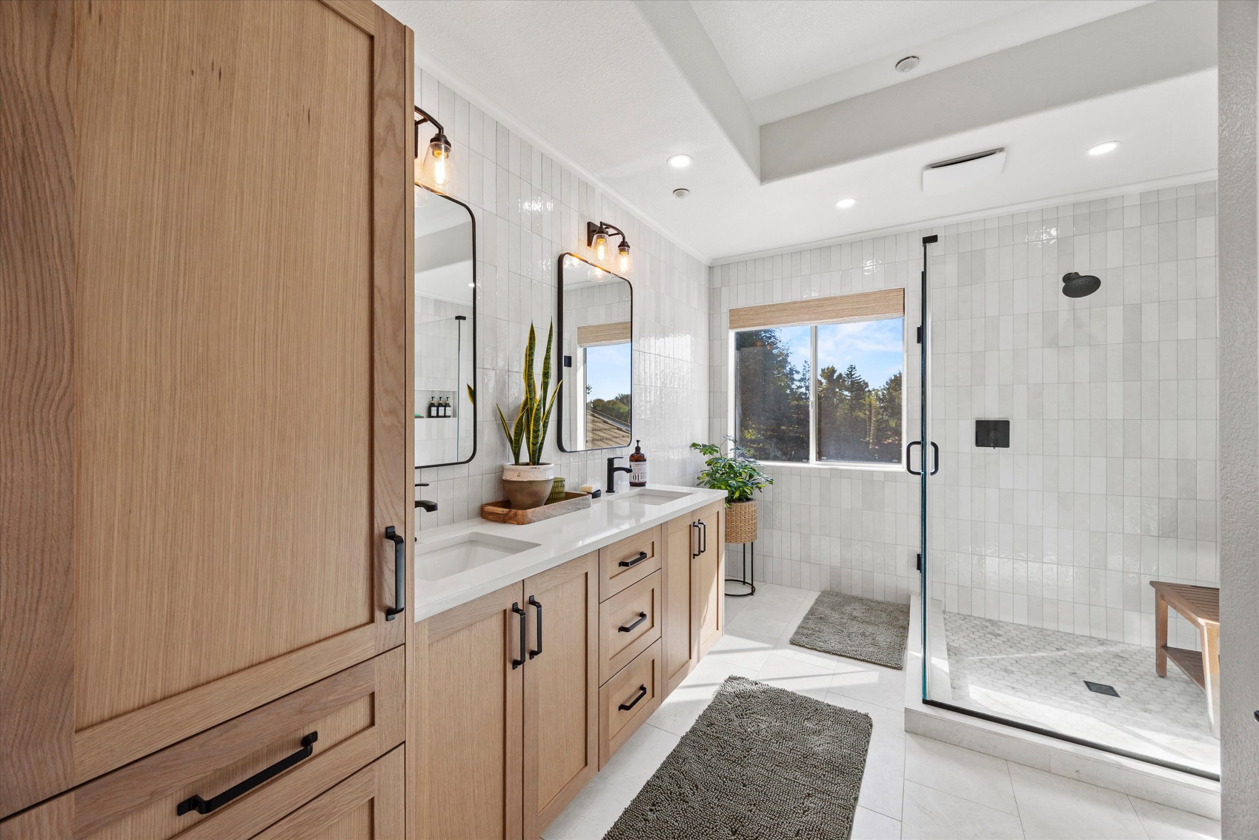 Custom oak vanity cabinetry with dual mirrors and walk-in shower in a remodeled bathroom